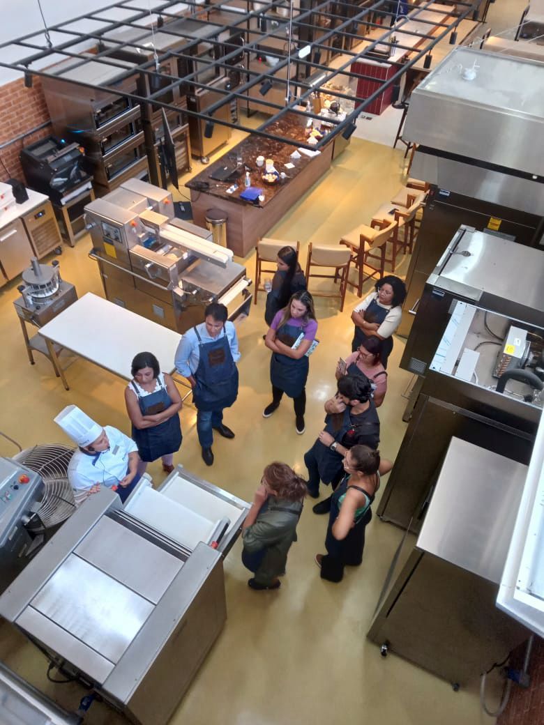 Um grupo de pessoas está em uma cozinha conversando entre si