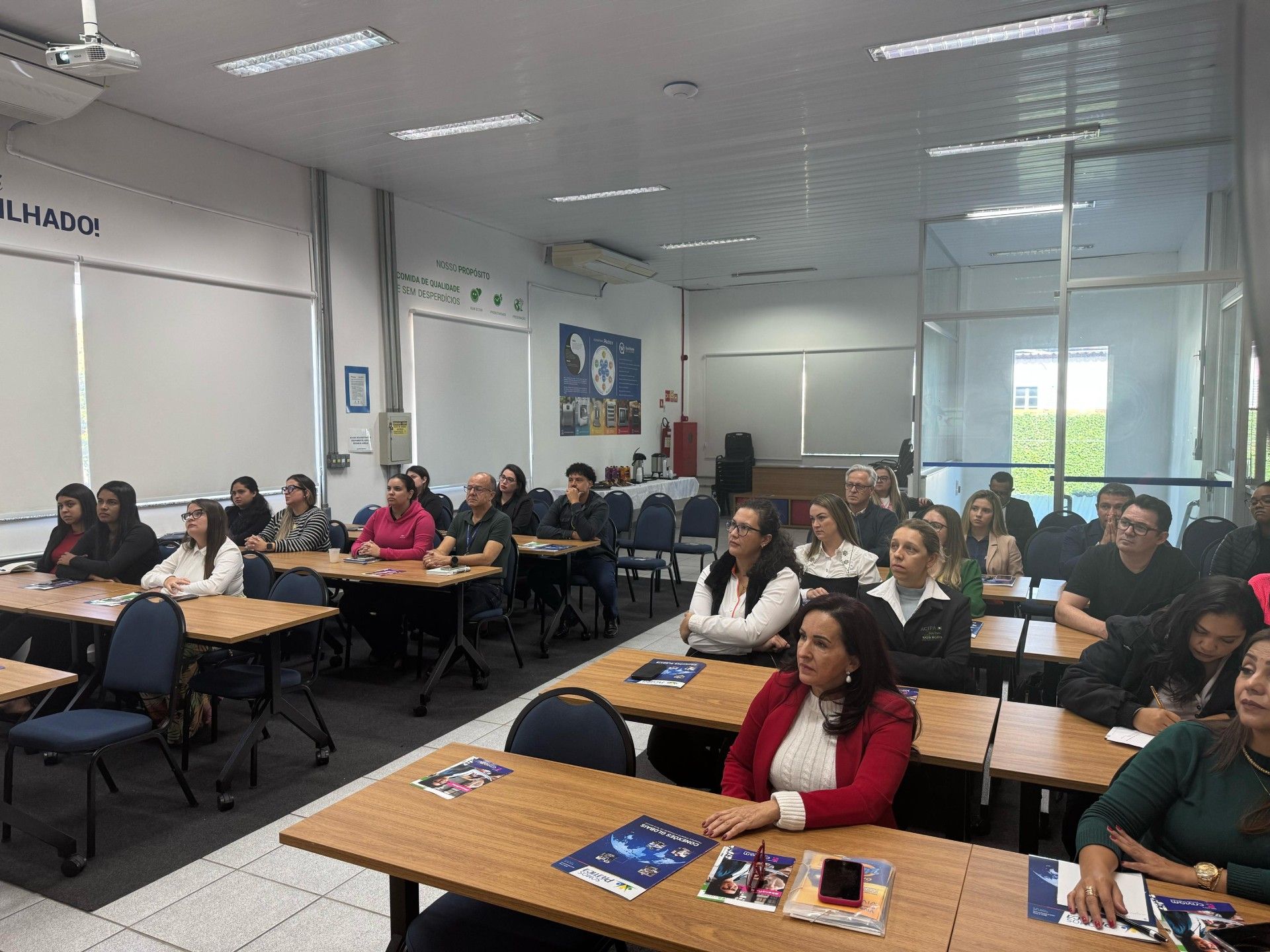 Um grupo de pessoas está sentado em mesas em uma sala de aula.
