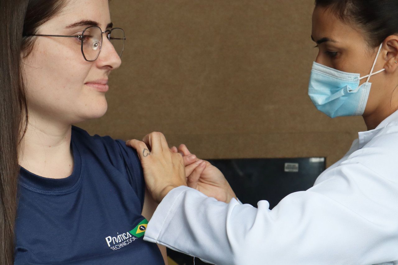 Uma mulher usando óculos está tomando vacina de um médico.