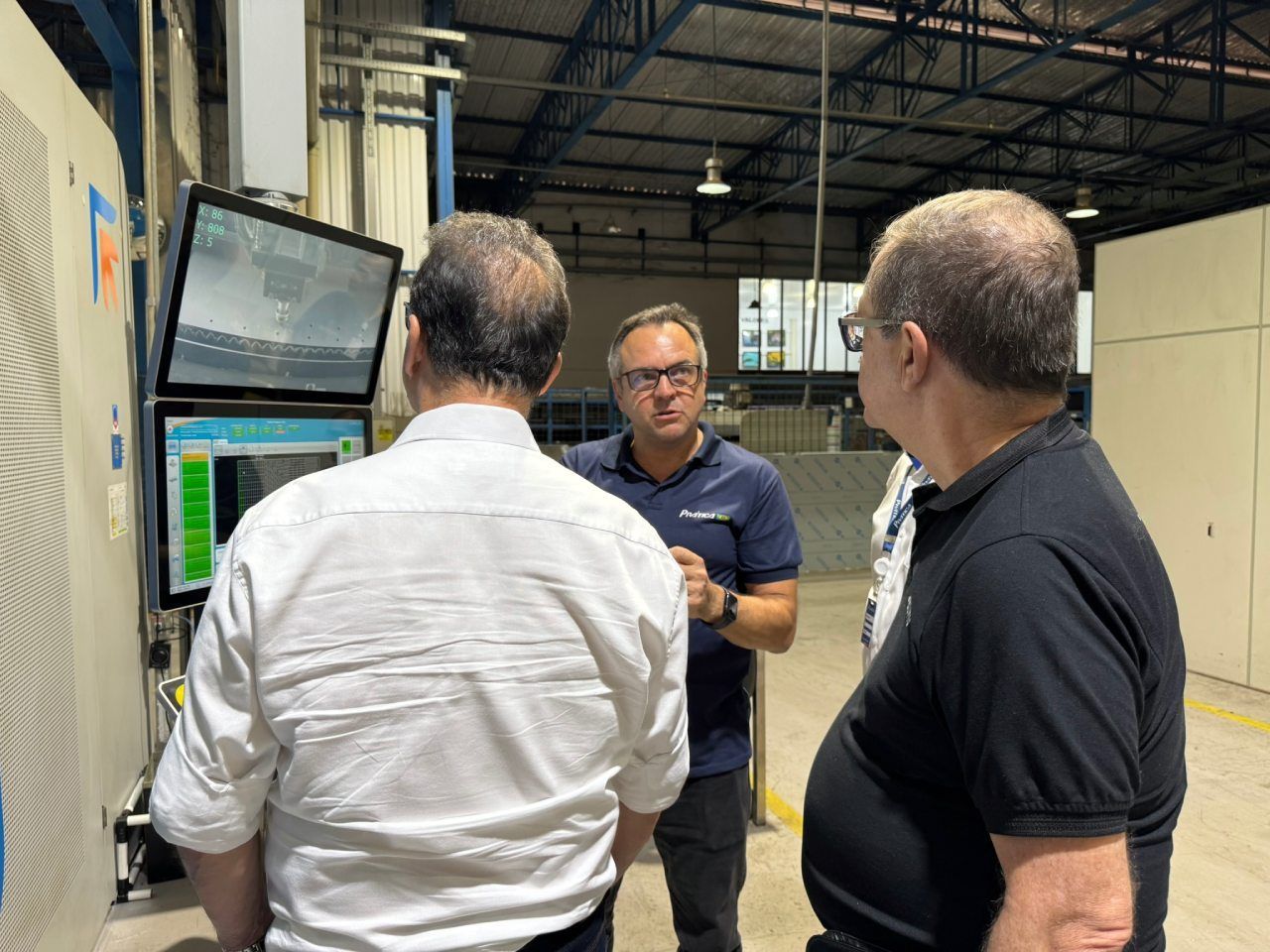 Três homens estão em um armazém olhando para uma tela de computador.