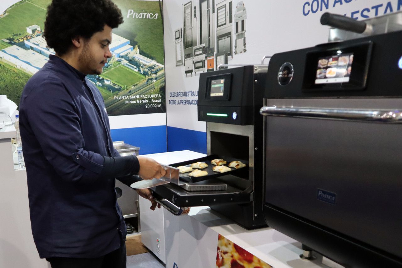 Um homem está tirando uma bandeja de biscoitos do forno.