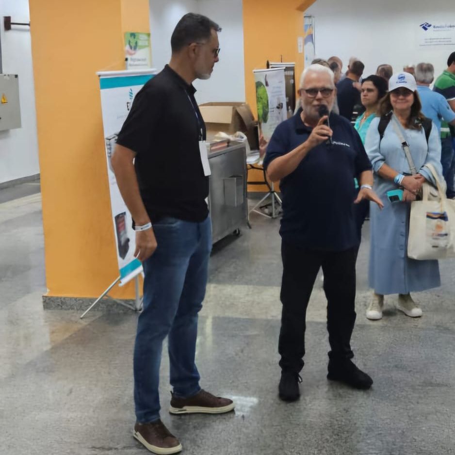 Um homem falando em um microfone na frente de um grupo de pessoas