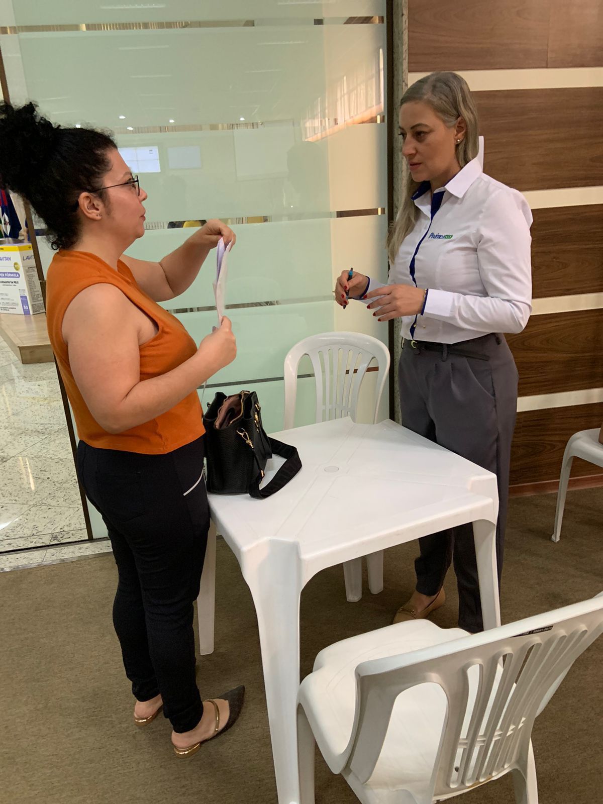 Duas mulheres estão de pé, uma ao lado da outra, em uma mesa.