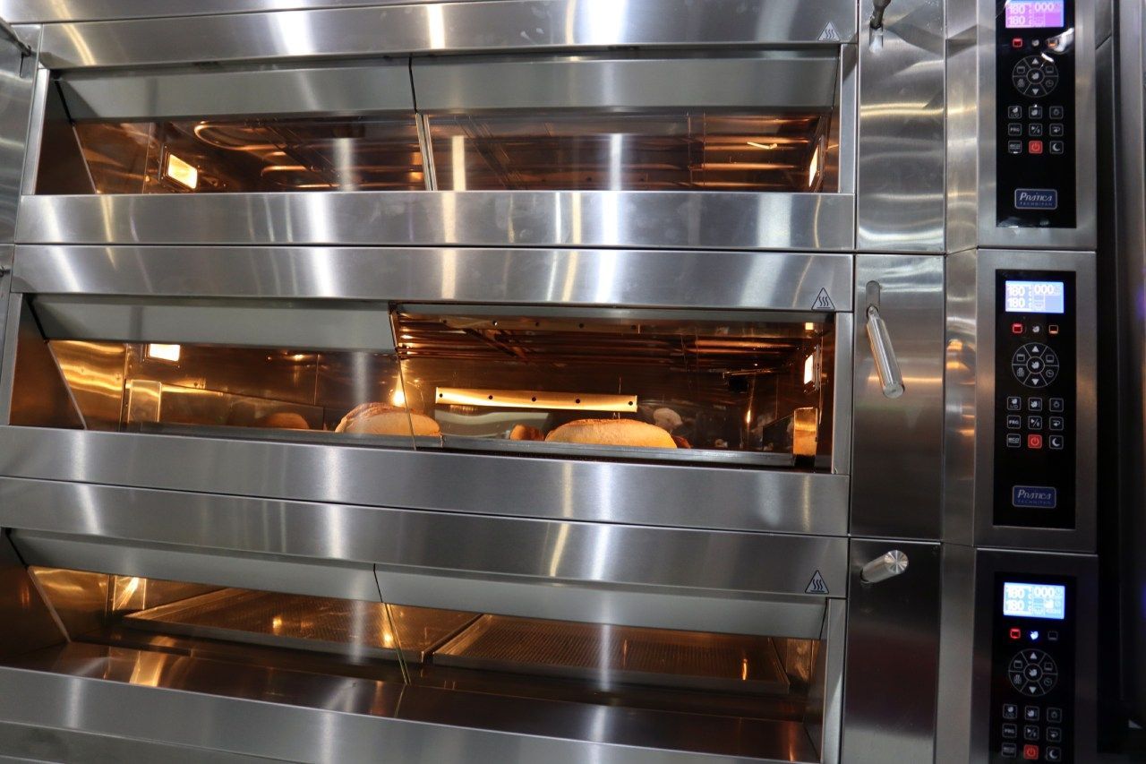 Um forno de aço inoxidável está sendo usado para assar pão