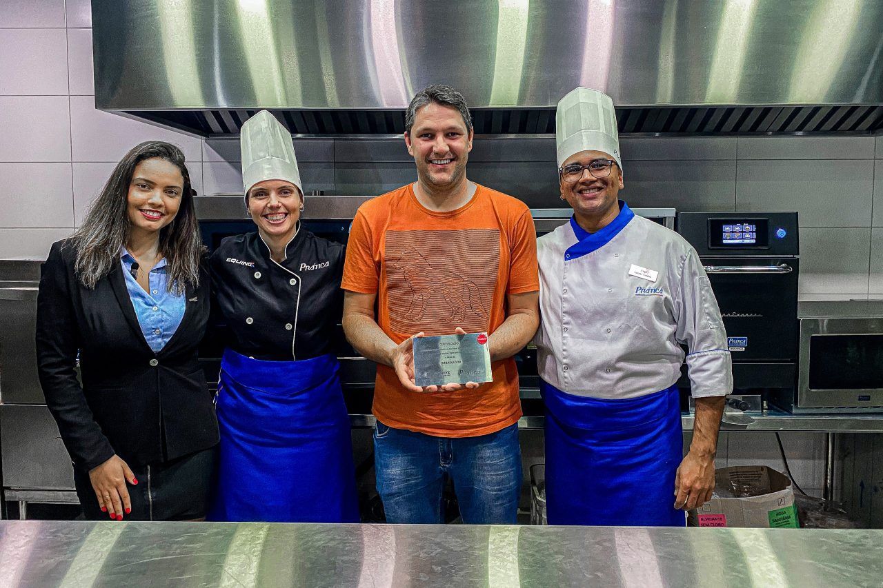 Um grupo de chefs está posando para uma foto em uma cozinha.
