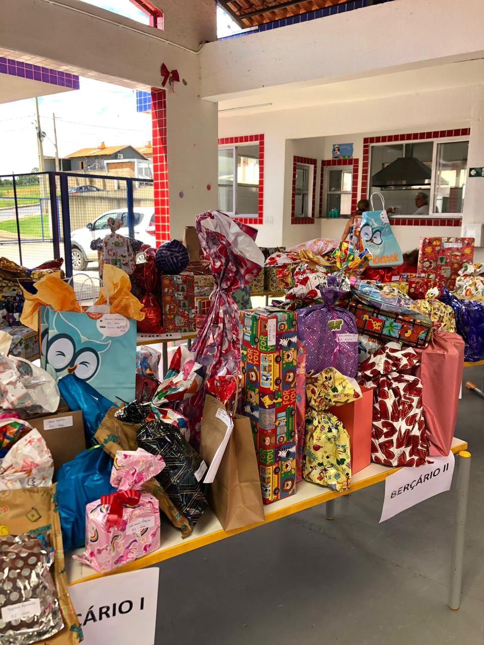 Uma mesa cheia de presentes embrulhados e sacolas.