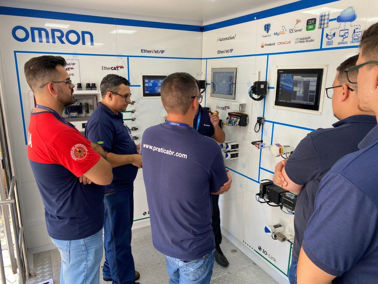 Um grupo de homens está em uma sala com uma placa que diz Omron.