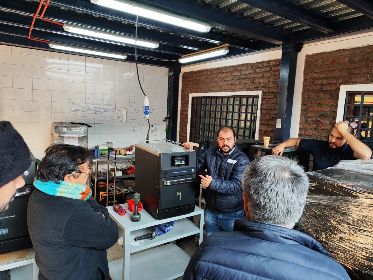 Um grupo de homens está em pé ao redor de uma máquina em uma sala.