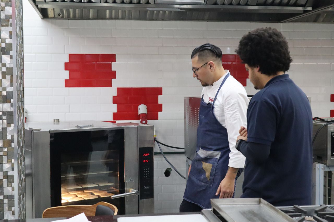 Dois homens estão em uma cozinha conversando.