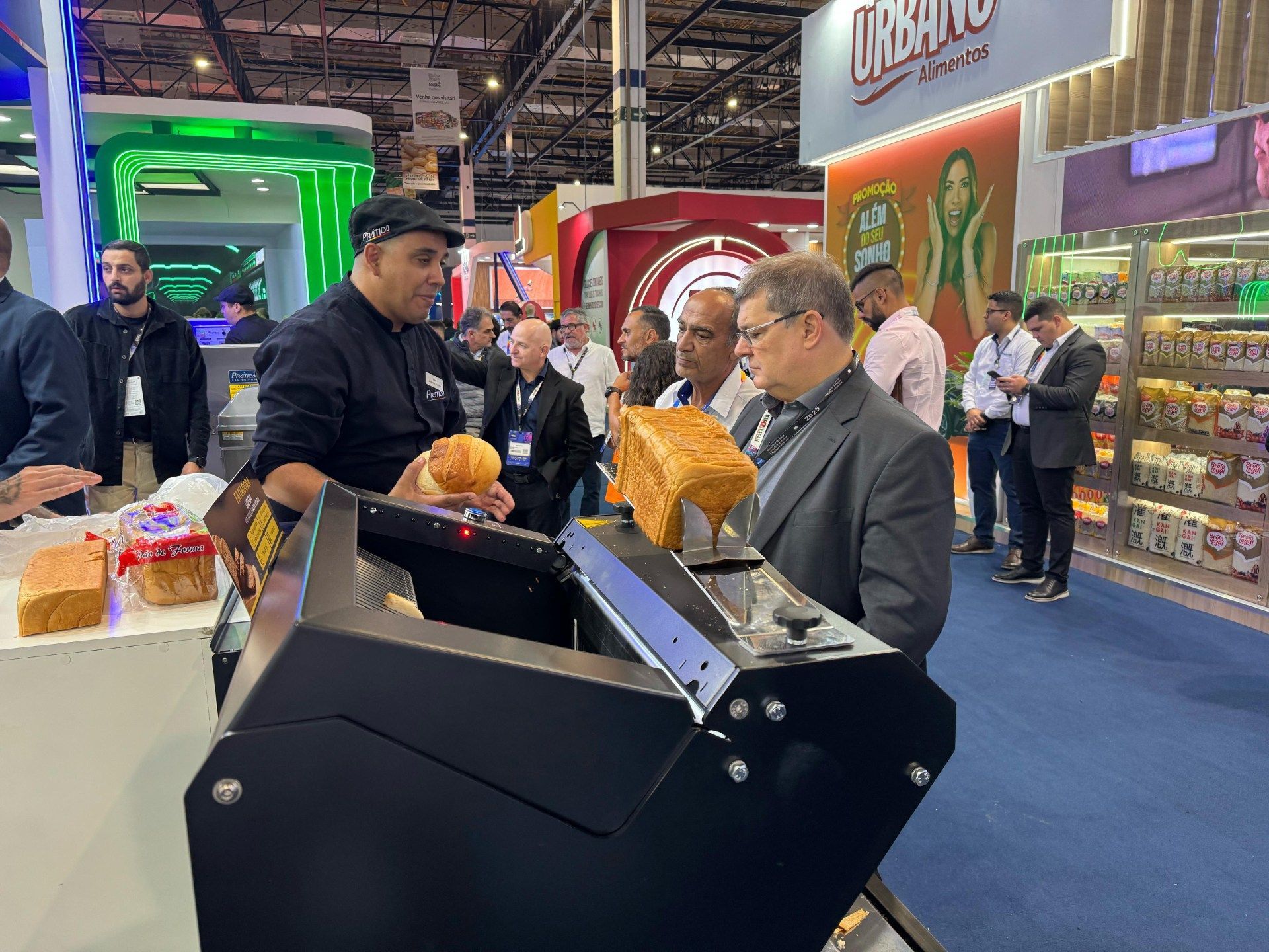 Um homem está segurando um pão na frente de uma máquina.