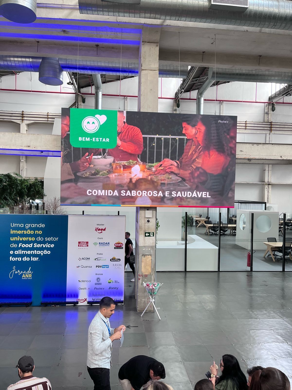 Um grupo de pessoas está em pé em frente a uma tela grande.