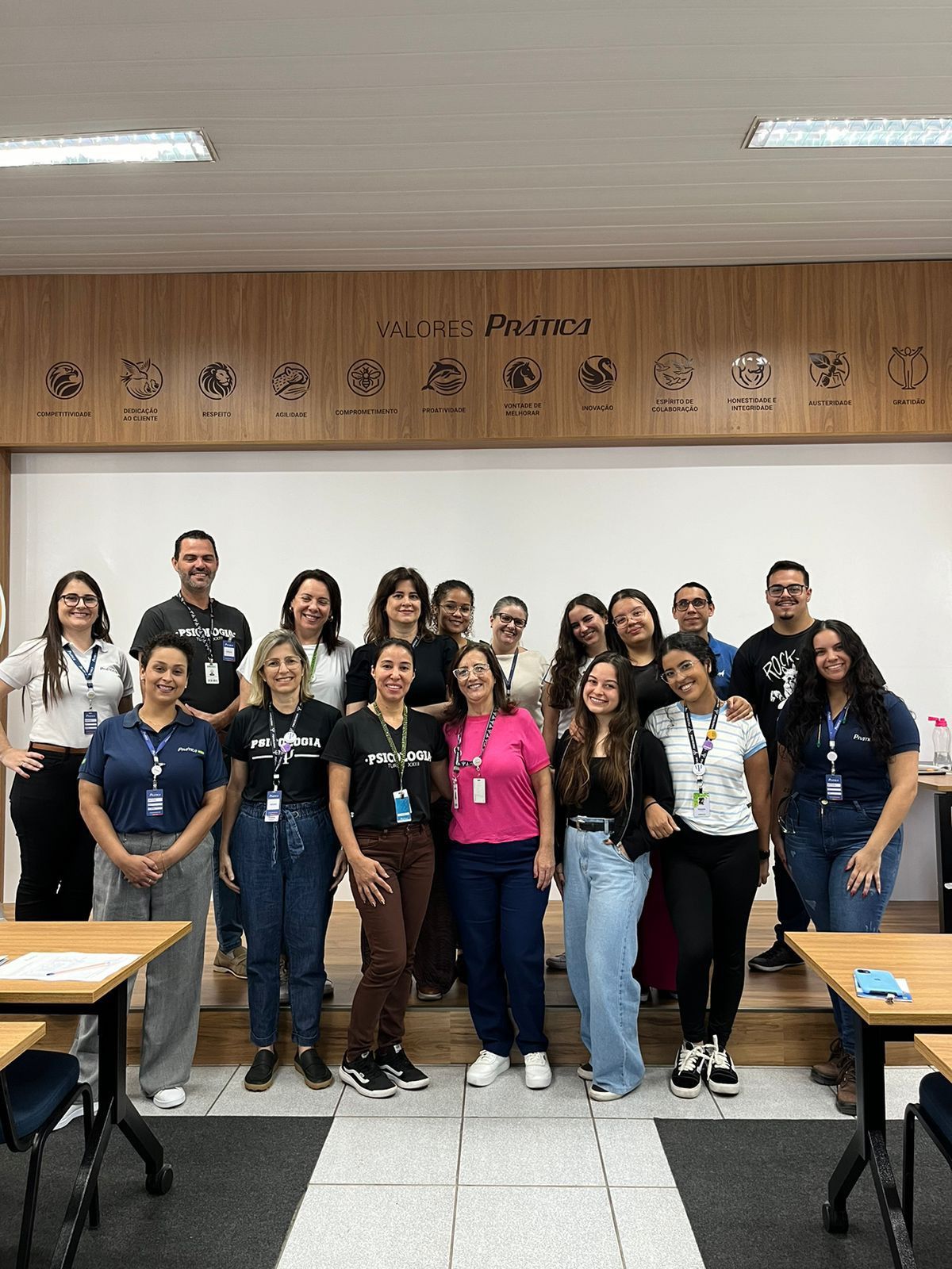 Um grupo de pessoas está posando para uma foto em uma sala de aula.