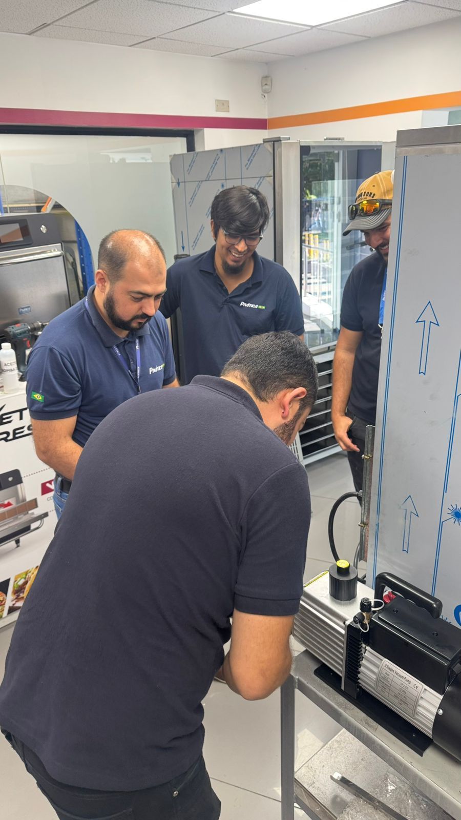 Quatro homens examinam máquinas em um espaço comercial bem iluminado