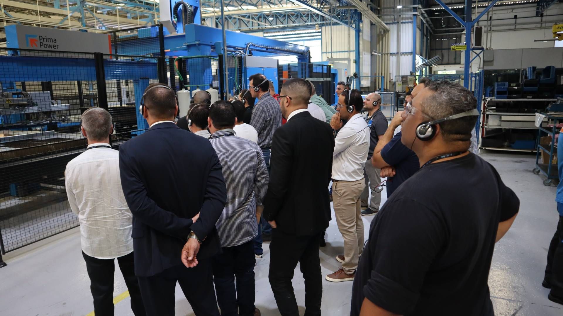 Um grupo de homens está em uma fábrica olhando para uma máquina.