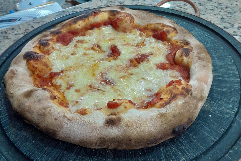 Uma pizza está em cima de uma tábua de corte de madeira.