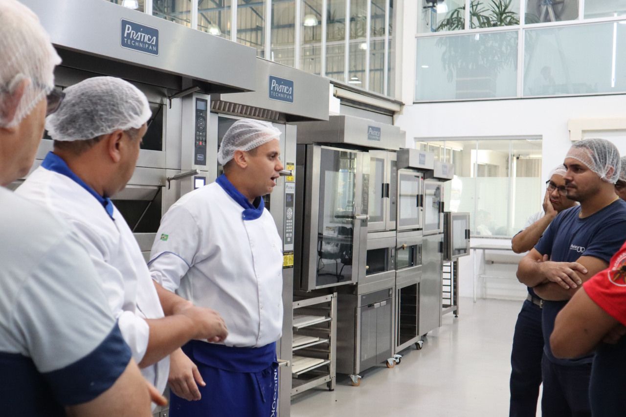 Um grupo de homens está em uma cozinha conversando entre si.