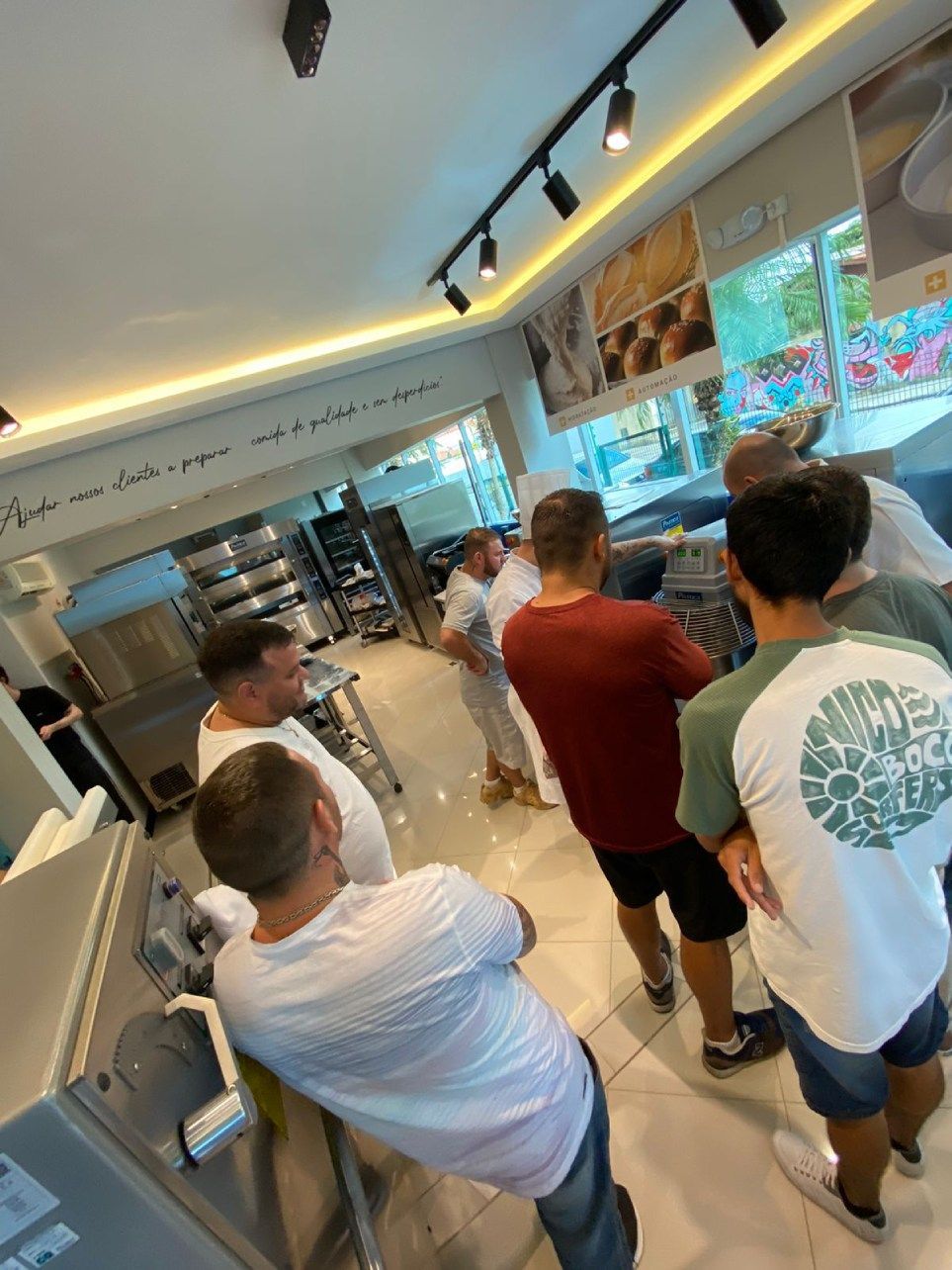 Um grupo de homens está em fila em uma padaria.