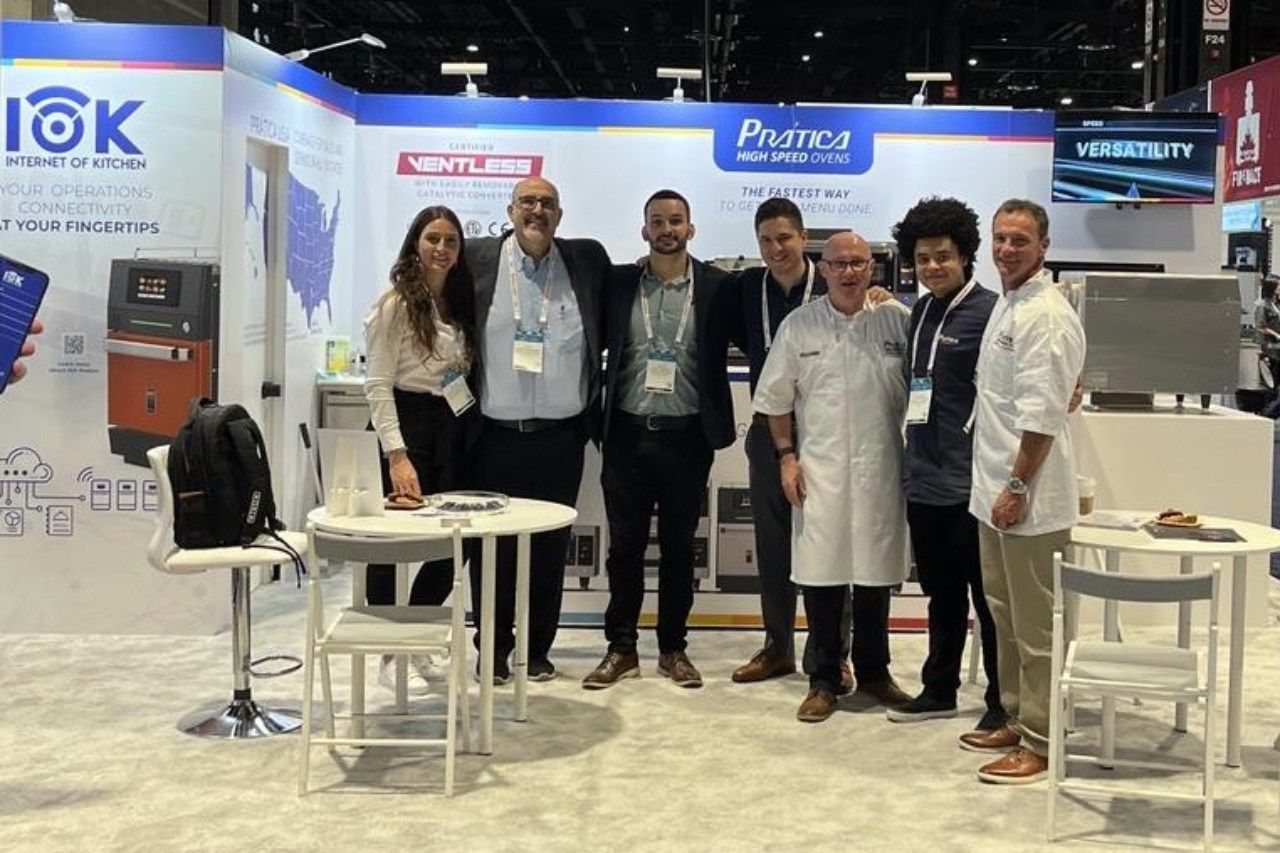 Um grupo de pessoas está posando para uma foto em frente a um estande em uma convenção.