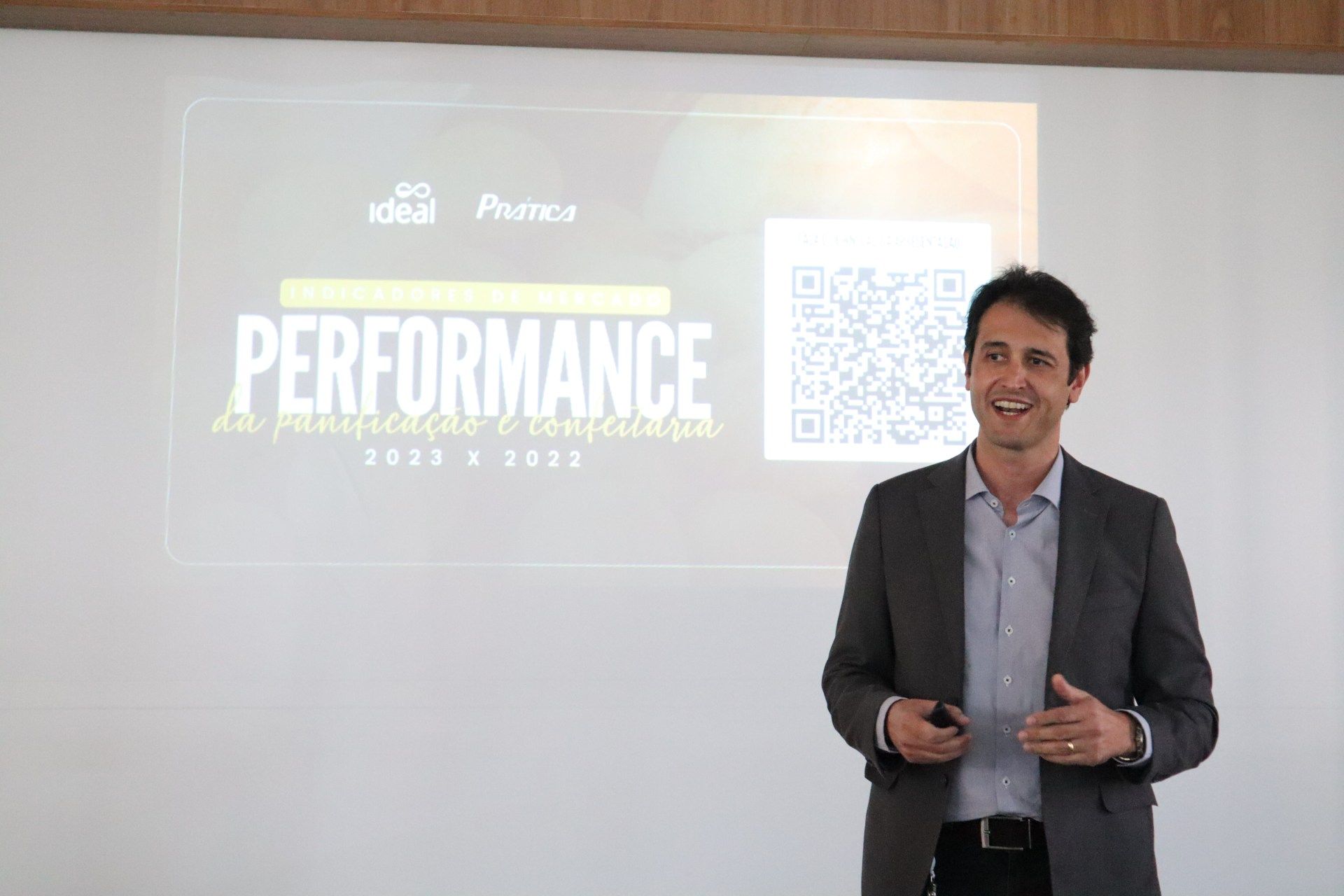 Um homem de terno está fazendo uma apresentação em frente a um quadro branco.