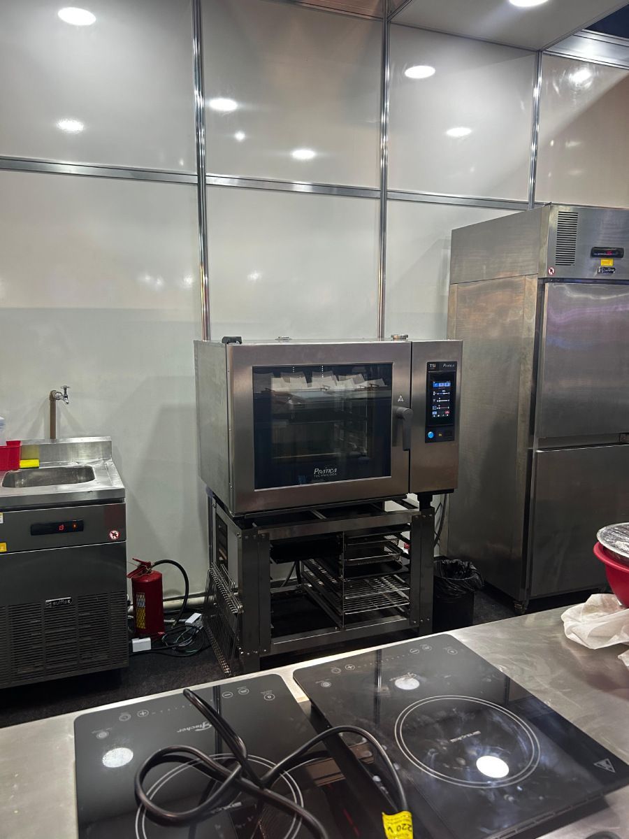 Uma cozinha com fogão, forno, geladeira e pia.