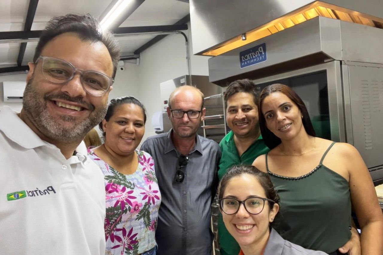 Um grupo de pessoas está posando para uma foto em uma cozinha.