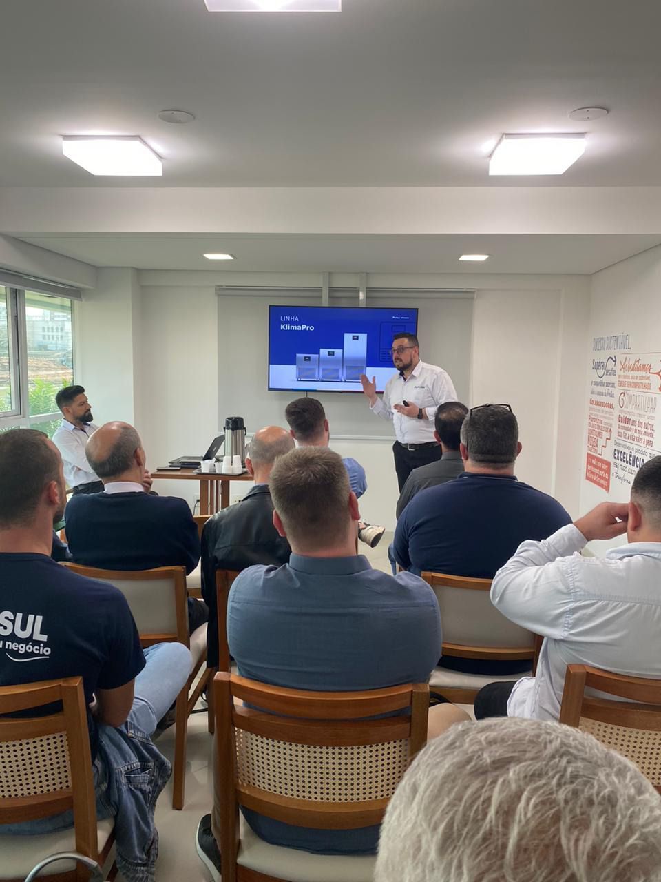 Um homem está fazendo uma apresentação para um grupo de pessoas sentadas em cadeiras.
