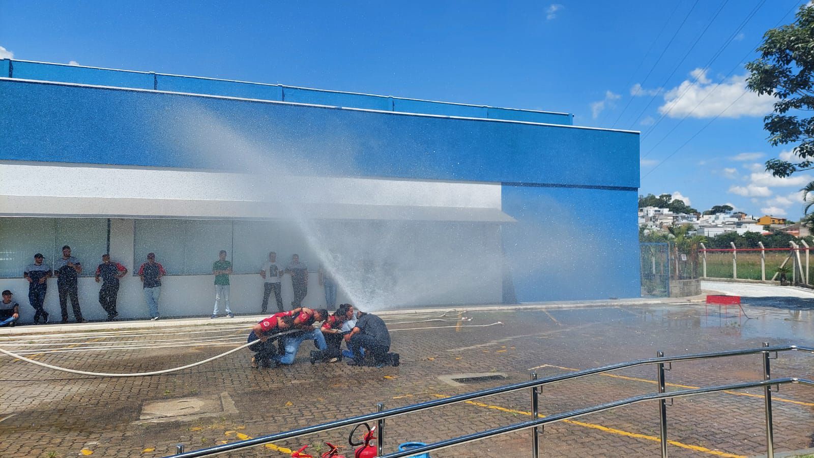 Um grupo de pessoas está em frente a um prédio azul borrifando água.