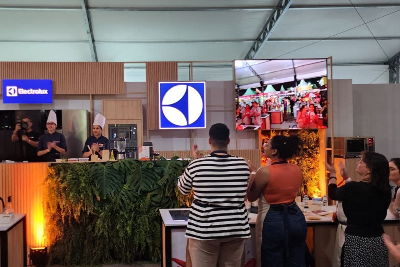 Um grupo de pessoas está em frente a um balcão de uma cozinha.