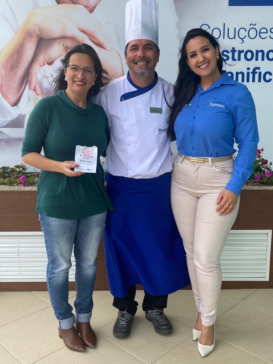 Um homem com chapéu de chef está posando para uma foto com duas mulheres