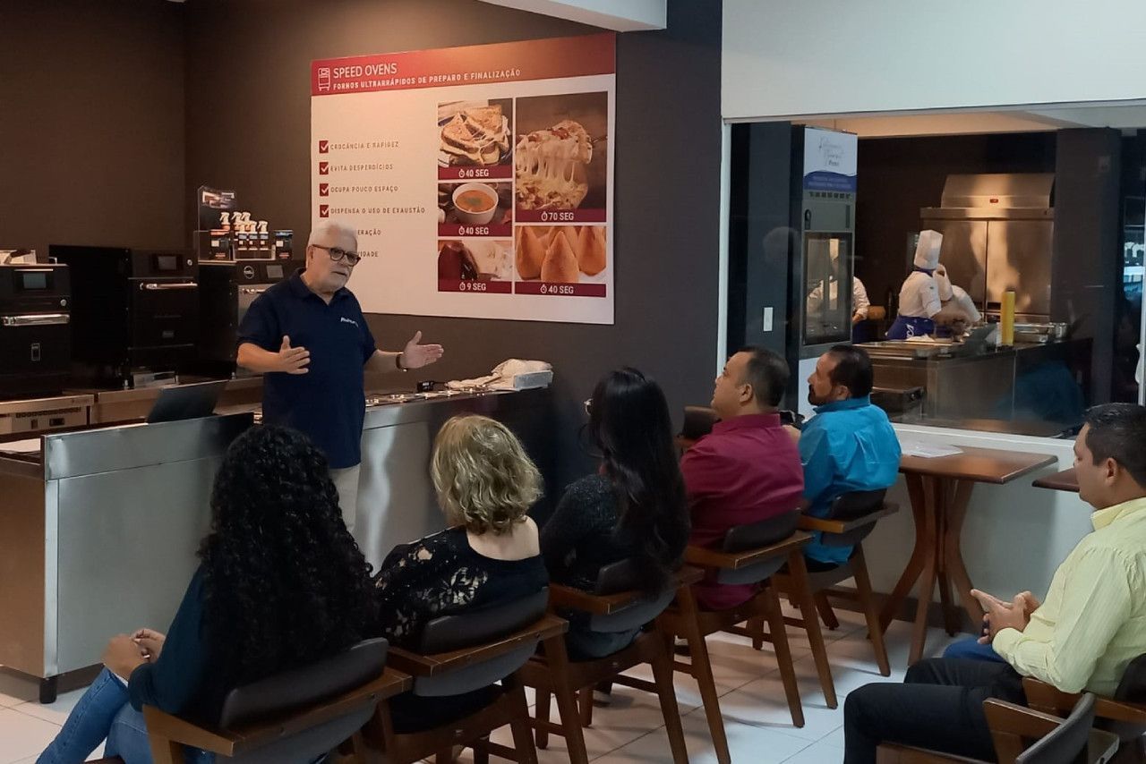 Um homem está fazendo uma apresentação para um grupo de pessoas em um restaurante.