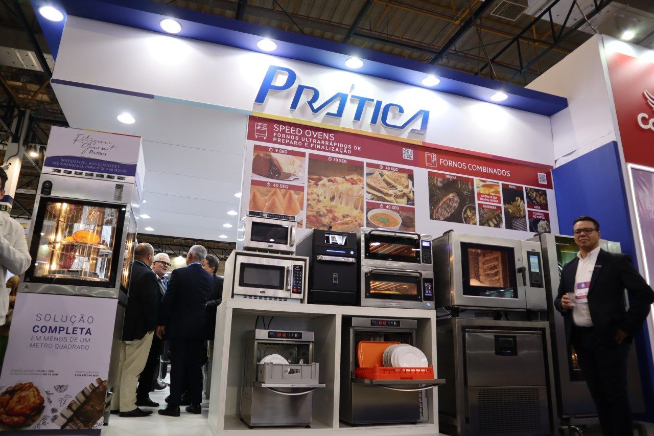 Um grupo de pessoas está em frente a uma exposição de fornos e micro-ondas.