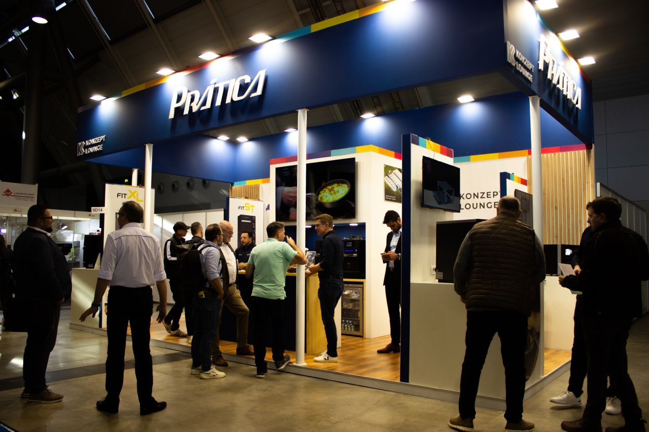 Um grupo de pessoas está em volta de um estande em uma convenção.