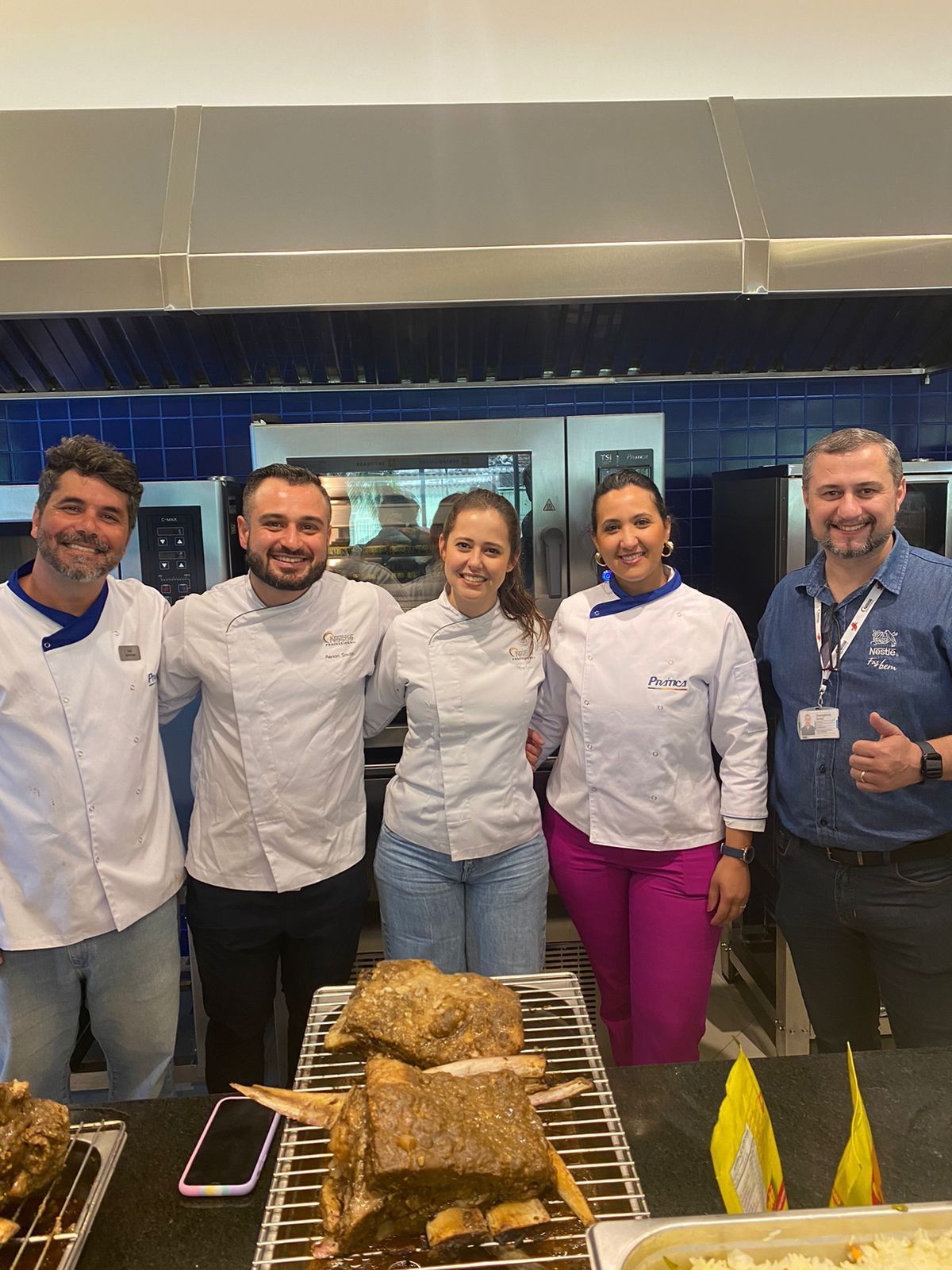 Um grupo de pessoas está posando para uma foto em uma cozinha.