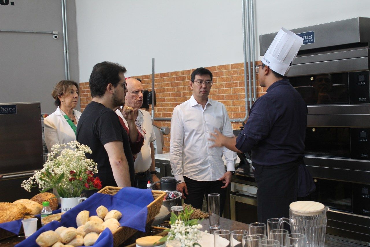 Um chef está conversando com um grupo de pessoas em uma cozinha.