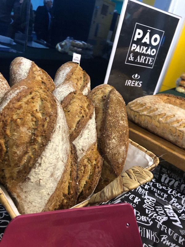 Uma cesta de pães está sobre uma mesa ao lado de uma placa.