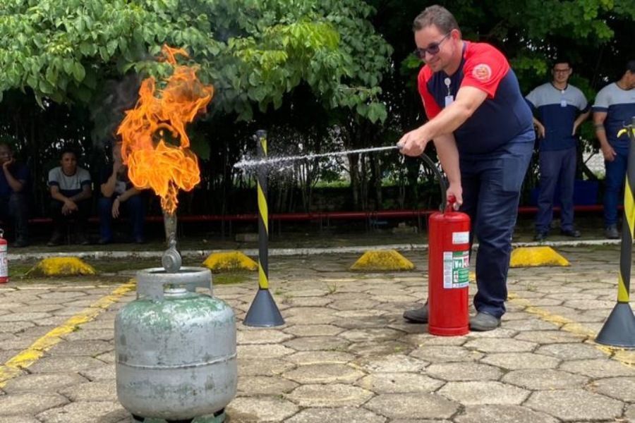 Um homem está usando um extintor de incêndio para apagar um incêndio.