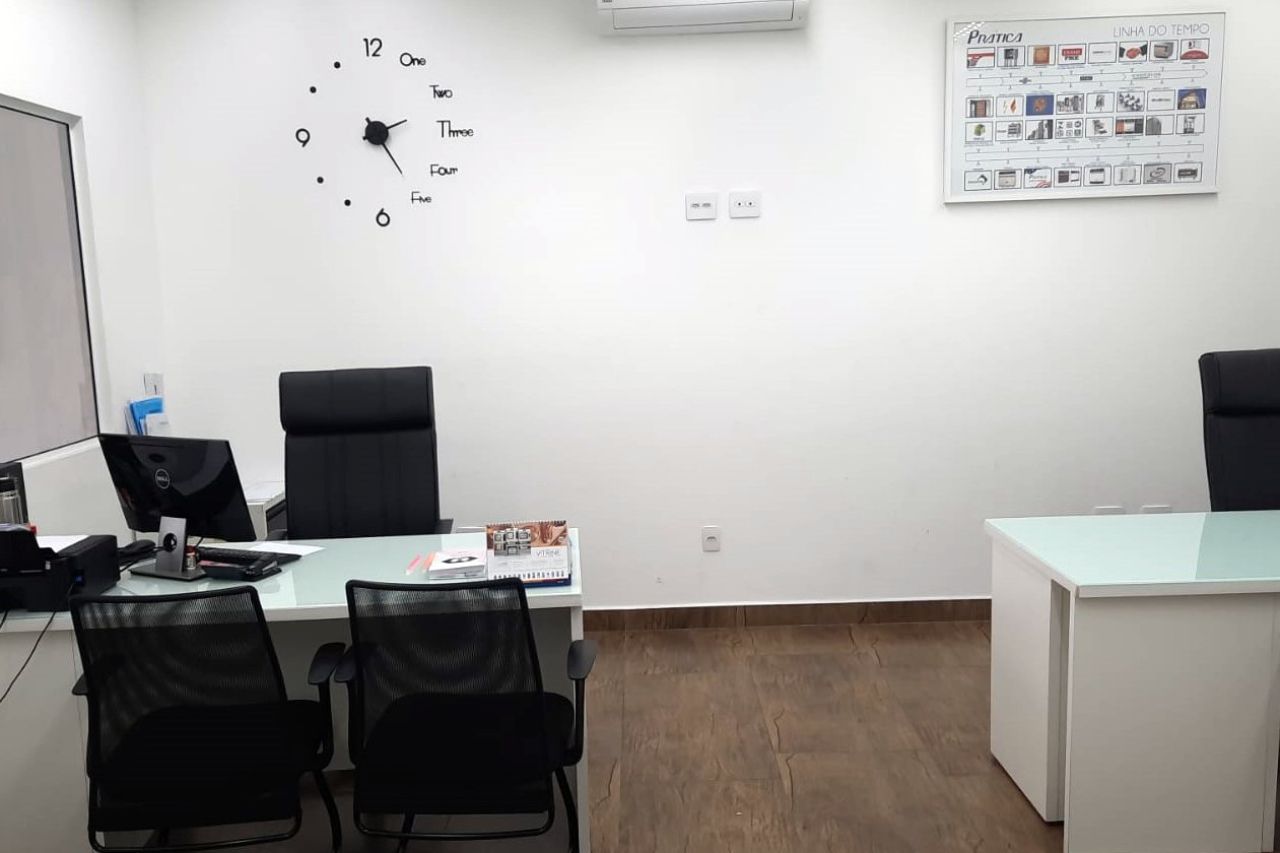 Há um relógio na parede acima da mesa no escritório.