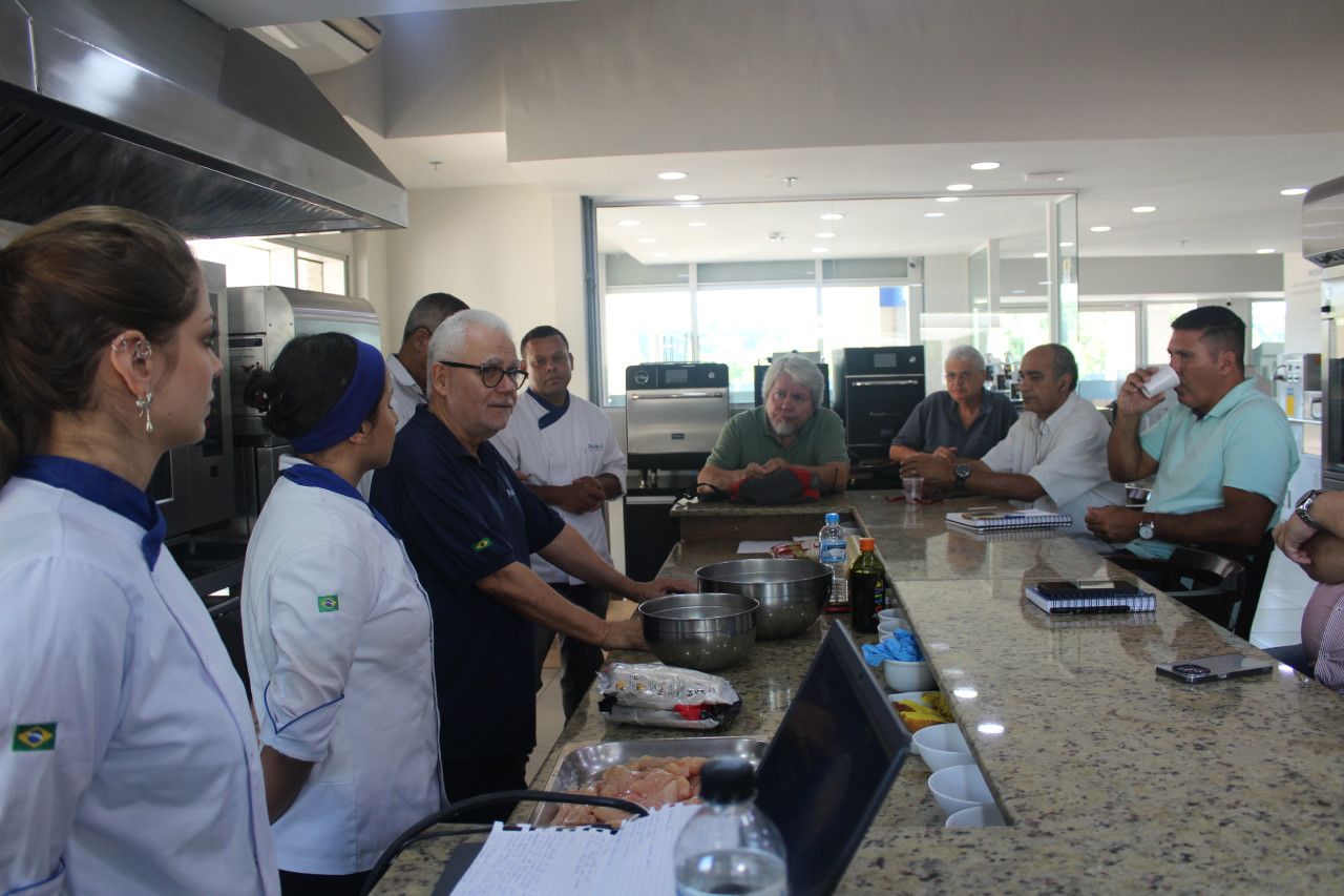 Um grupo de pessoas está em pé ao redor de um balcão na cozinha.
