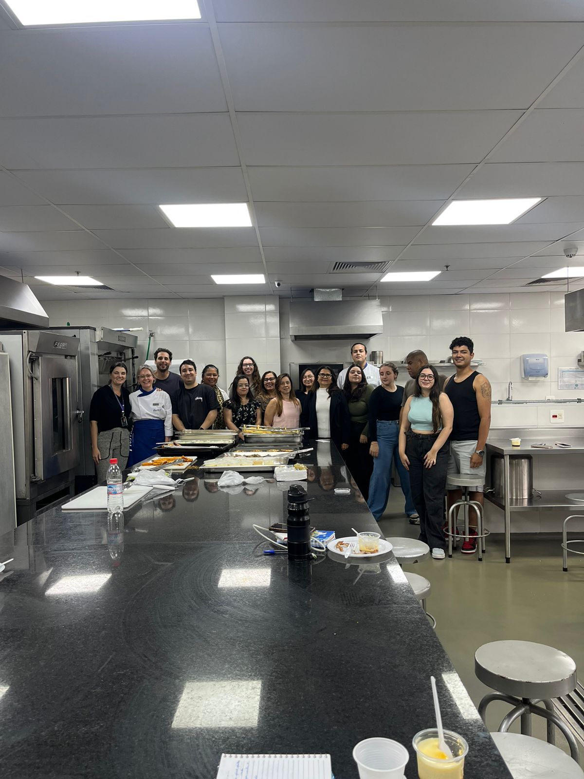 Um grupo de pessoas está posando para uma foto em uma cozinha.