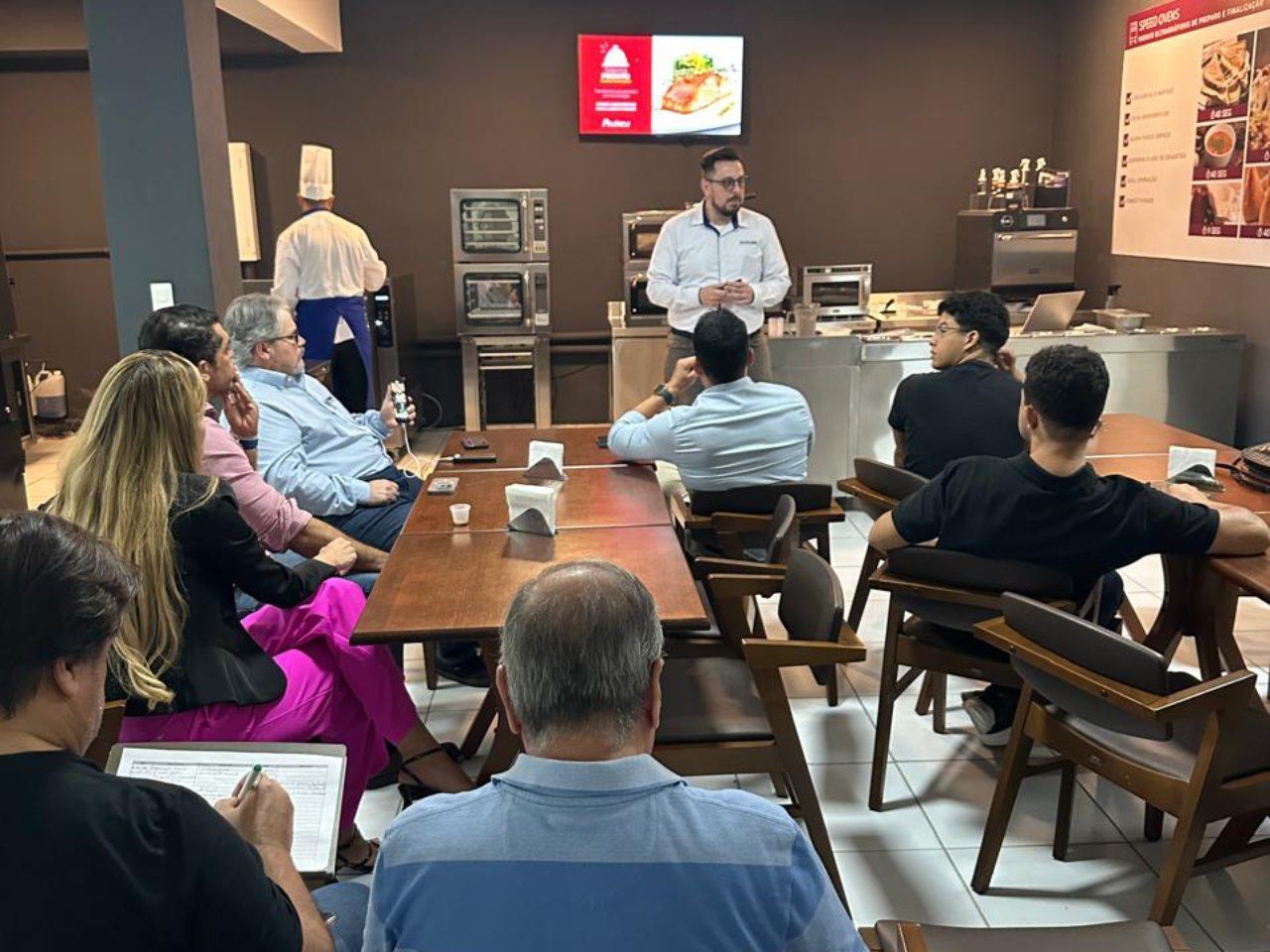 Um grupo de pessoas está sentado em mesas em uma sala.
