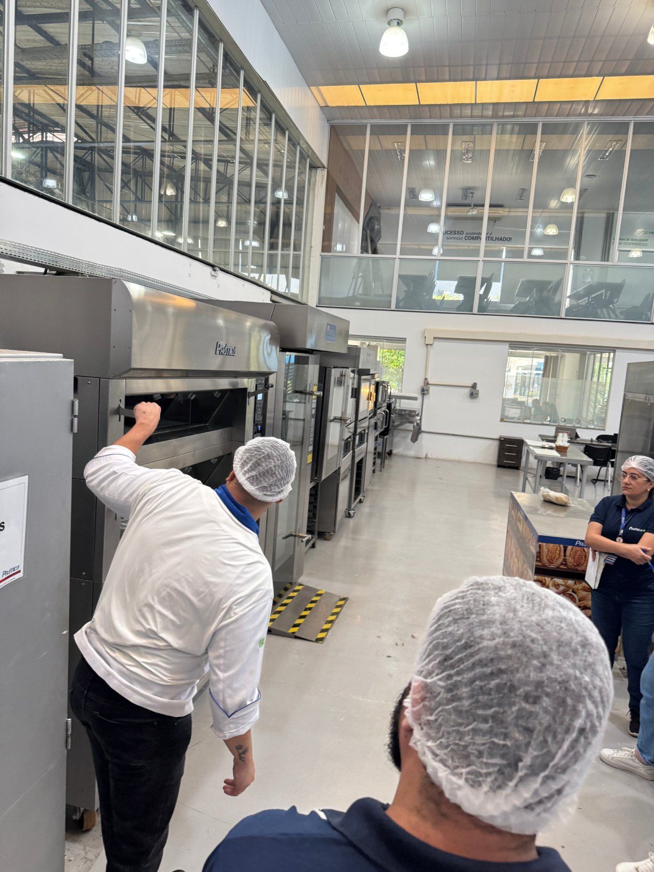 Um homem com um chapéu branco está parado em frente a um forno.