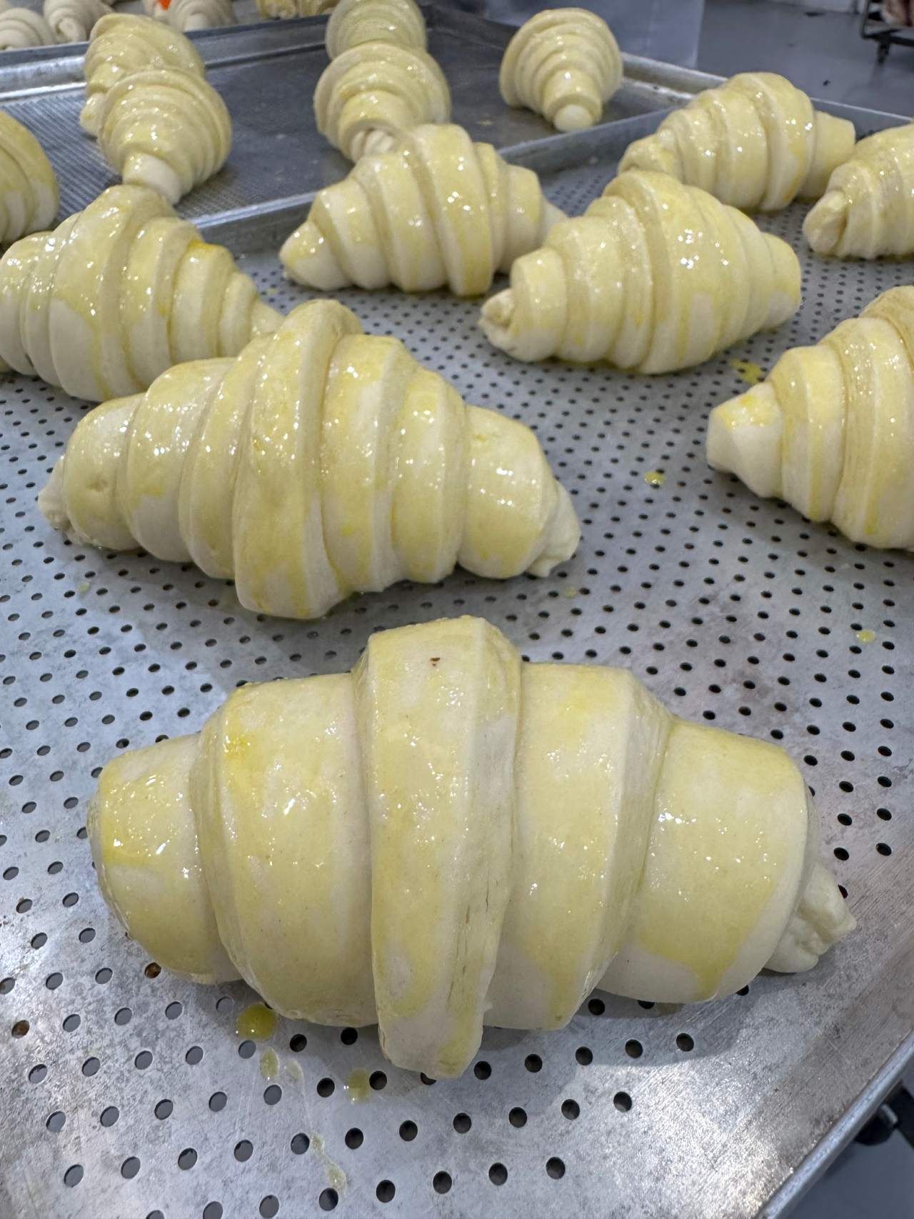 Um monte de croissants estão em cima de uma forma perfurada.