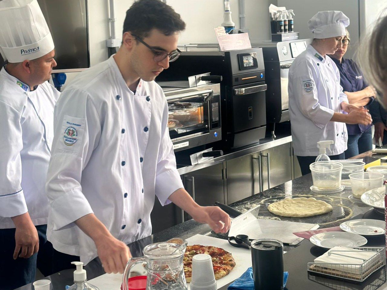Um grupo de chefs está preparando comida em uma cozinha.