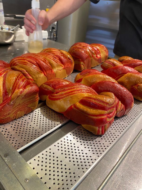 Uma pessoa está borrifando um monte de pão com um borrifador.