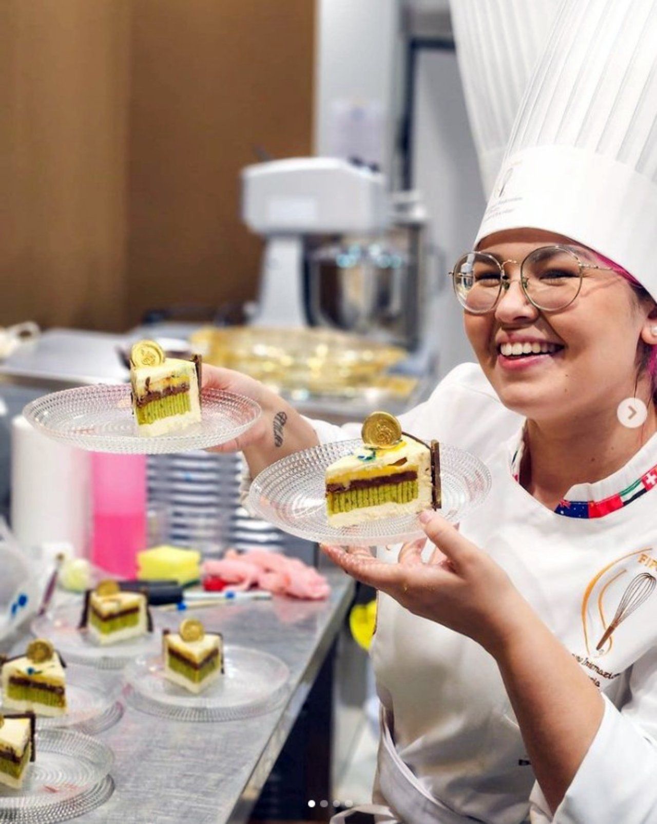 Uma mulher com chapéu de chef está segurando um prato de comida.