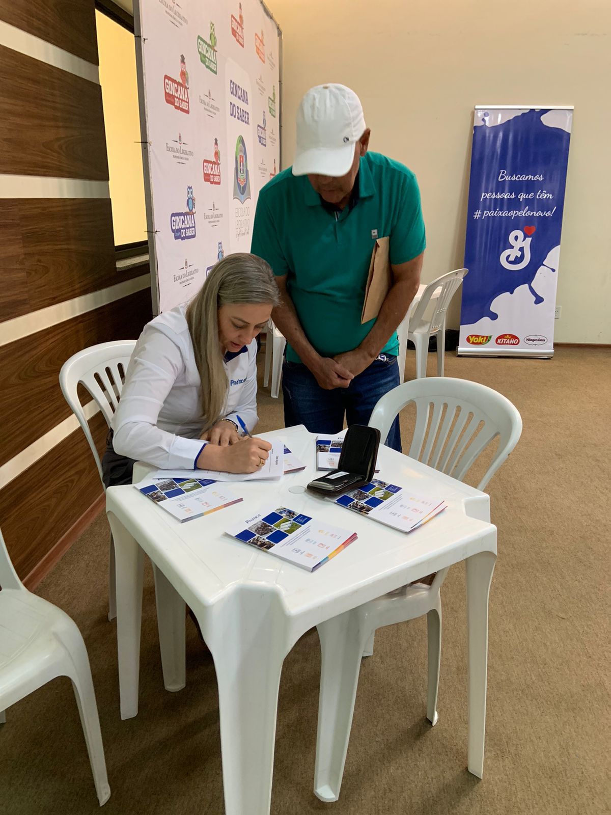 Um homem e uma mulher estão sentados à mesa assinando papéis.