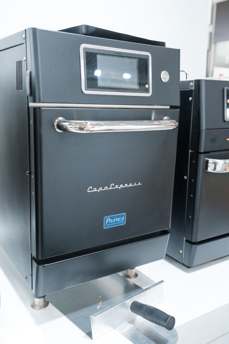 Um forno preto está sobre uma mesa ao lado de outro forno.