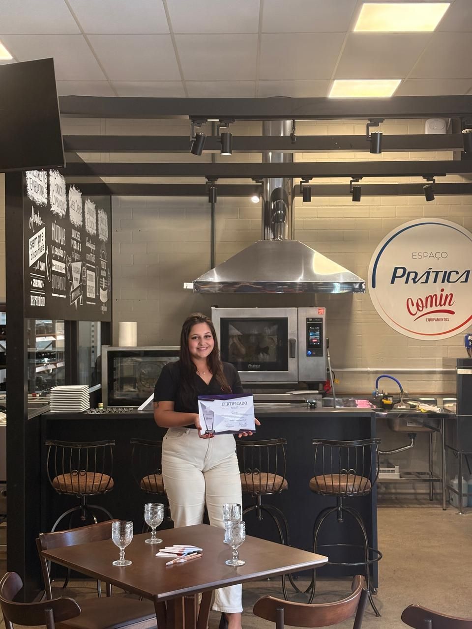 Uma mulher está parada na cozinha segurando um certificado.