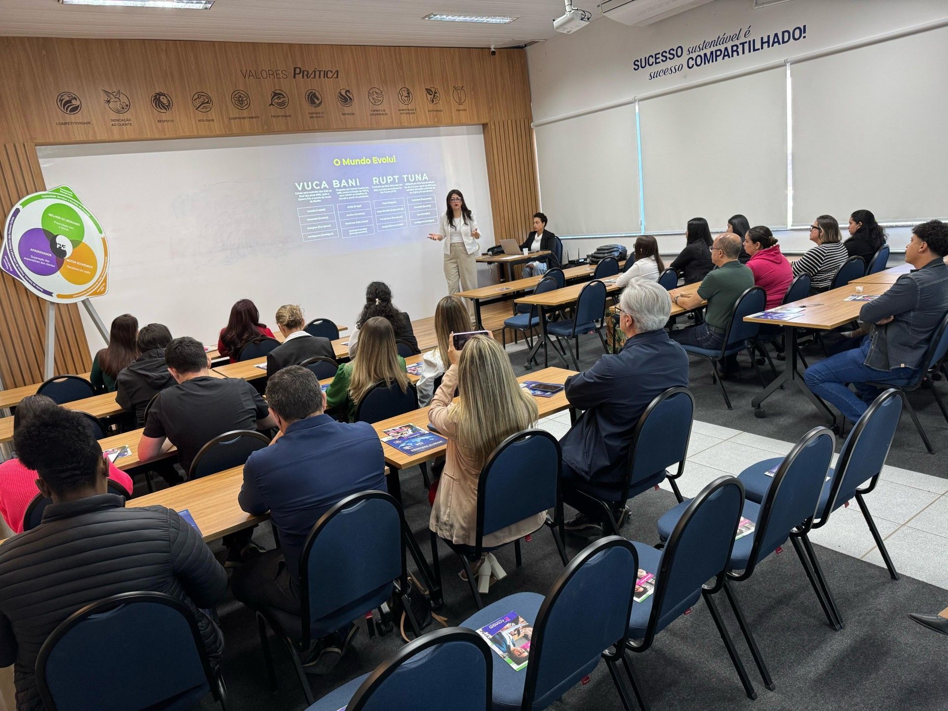 Um grupo de pessoas está sentado em mesas em uma sala de aula.