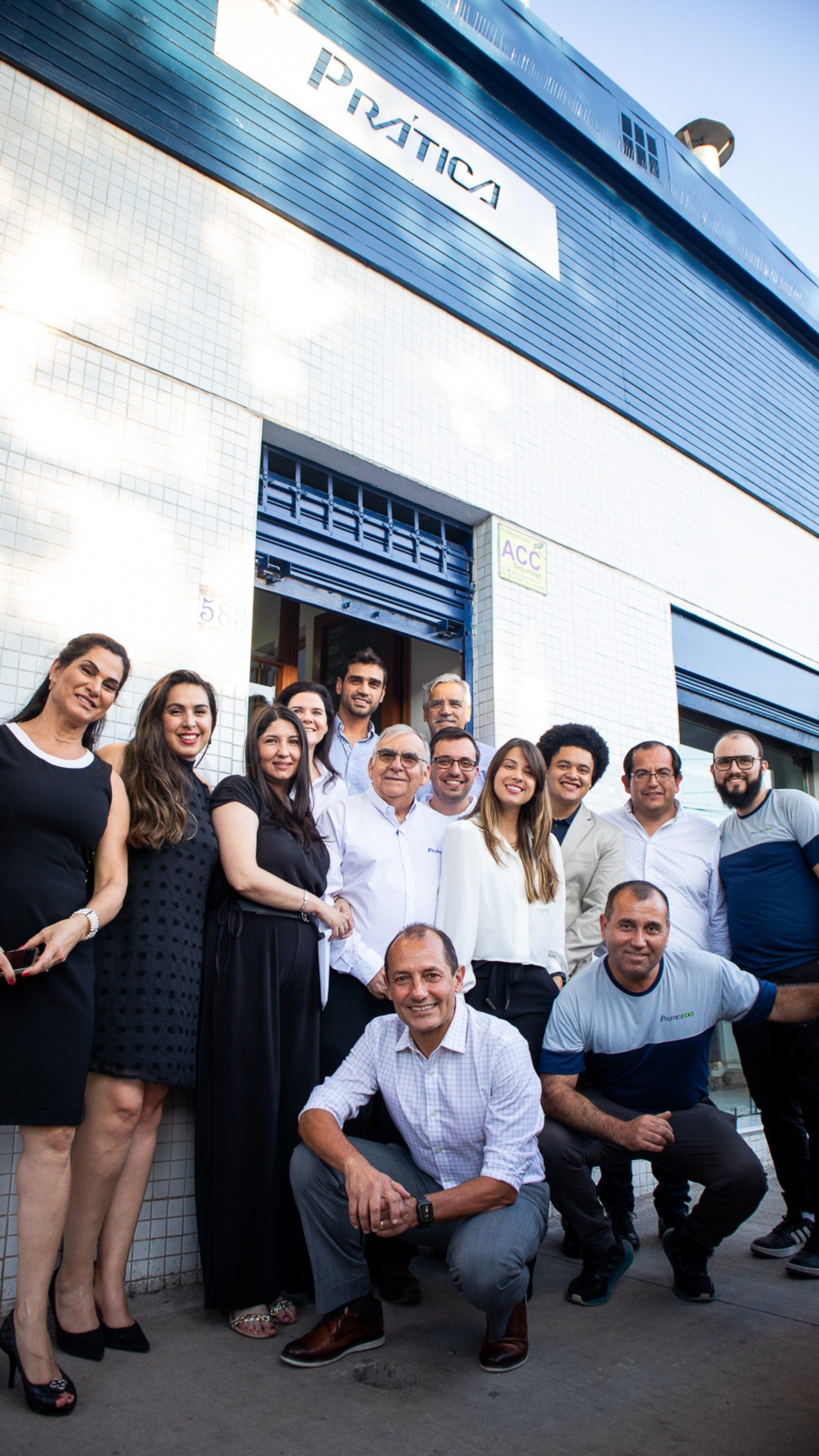 Um grupo de pessoas está posando para uma foto em frente a um prédio.